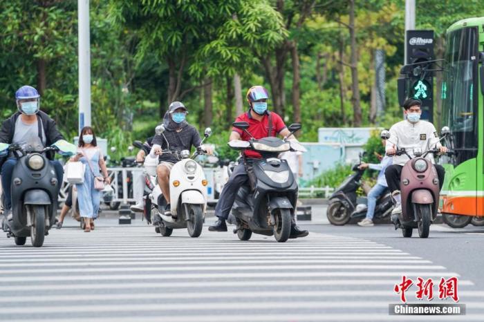 资料图：广西南宁，电动车驾驶员佩戴头盔骑行。中新社记者 陈冠言 摄