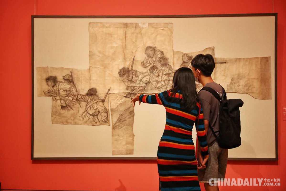 观众欣赏展出作品《八女投江》素描稿.(中国日报记者 姜东 摄)