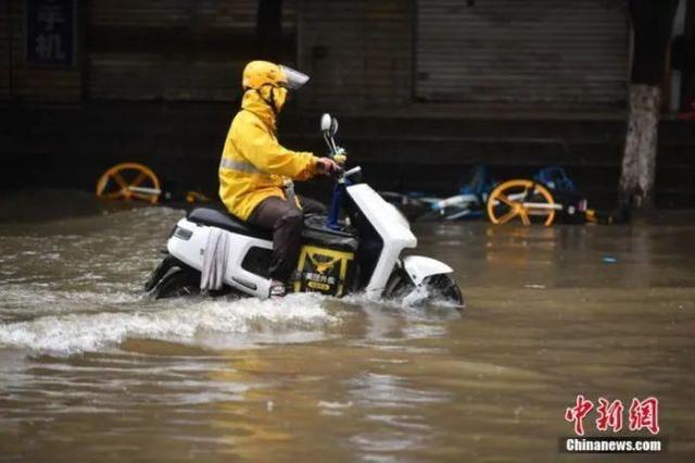 资料图：外卖小哥通过积水路段。中新社记者 刘冉阳 摄