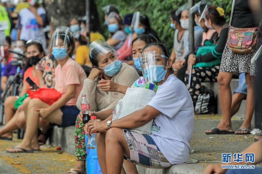戴口罩的人们在菲律宾马尼拉排队等待领取物资。