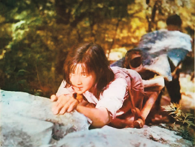 图为电影《小花》剧照:何翠姑(刘晓庆饰)跪抬担架送伤员  本文配图