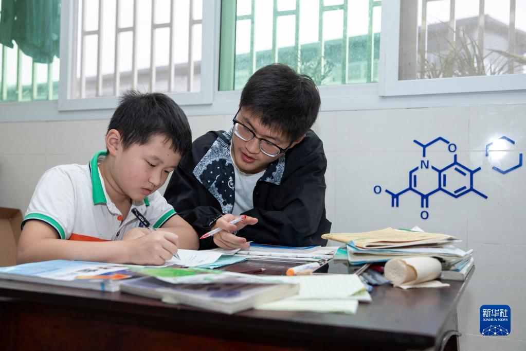 雷波中学高2021届毕业生刘取（右）在家中指导还在上小学的弟弟刘予做暑假作业。他今年被清华大学土木类专业录取（8月26日摄）。新华社记者 沈伯韩 摄