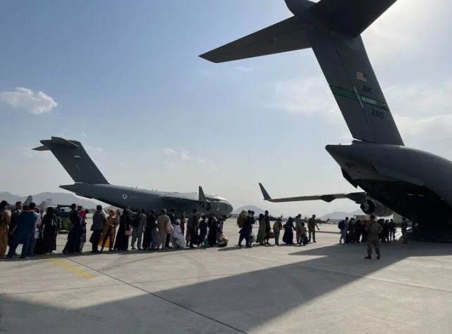 2021年8月22日，人们在阿富汗首都喀布尔国际机场排队登上美国军用飞机离开。新华社发