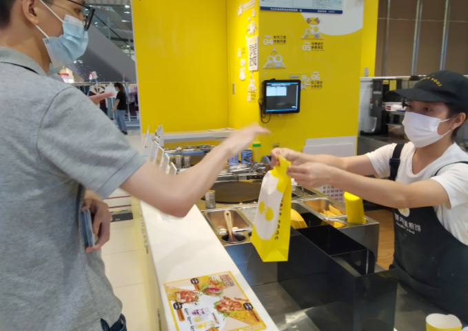 在广州一商场，店家用纸袋给顾客打包食品 图片来源：新华社记者 卢汉欣 摄