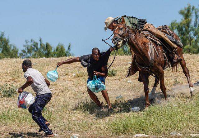 美国得克萨斯州德尔里奥，一名骑马的美国边境巡逻人员试图阻止一名海地移民进入阿库纳德尔里约热内卢国际大桥附近的格兰德河岸边的营地。图源：视觉中国