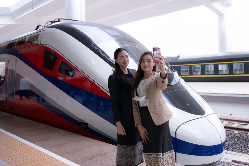 10月16日，两名女子在老挝万象站与“澜沧号”动车组合影。凯乔摄