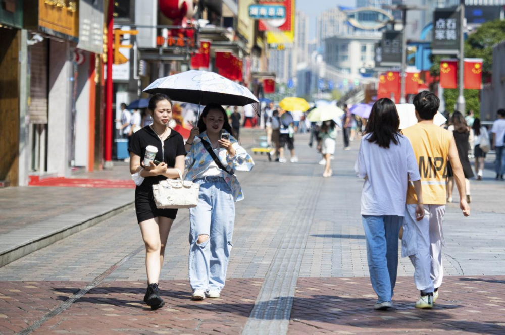 图为10月4日,行人在湖南长沙黄兴路步行街打伞防晒.