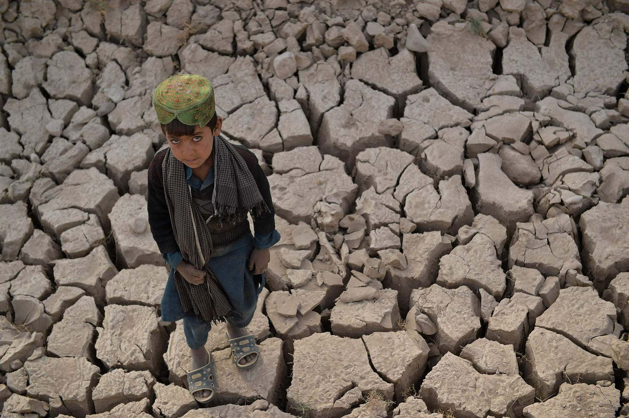 当地时间2021年10月15日，阿富汗巴德吉斯省，一个孩子站在干裂的土地上。图源：视觉中国