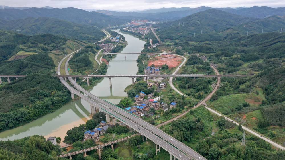 动车行经贵广高铁三江侗族自治县程村乡泗里村路段（无人机照片）。新华社发（龚普康 摄）