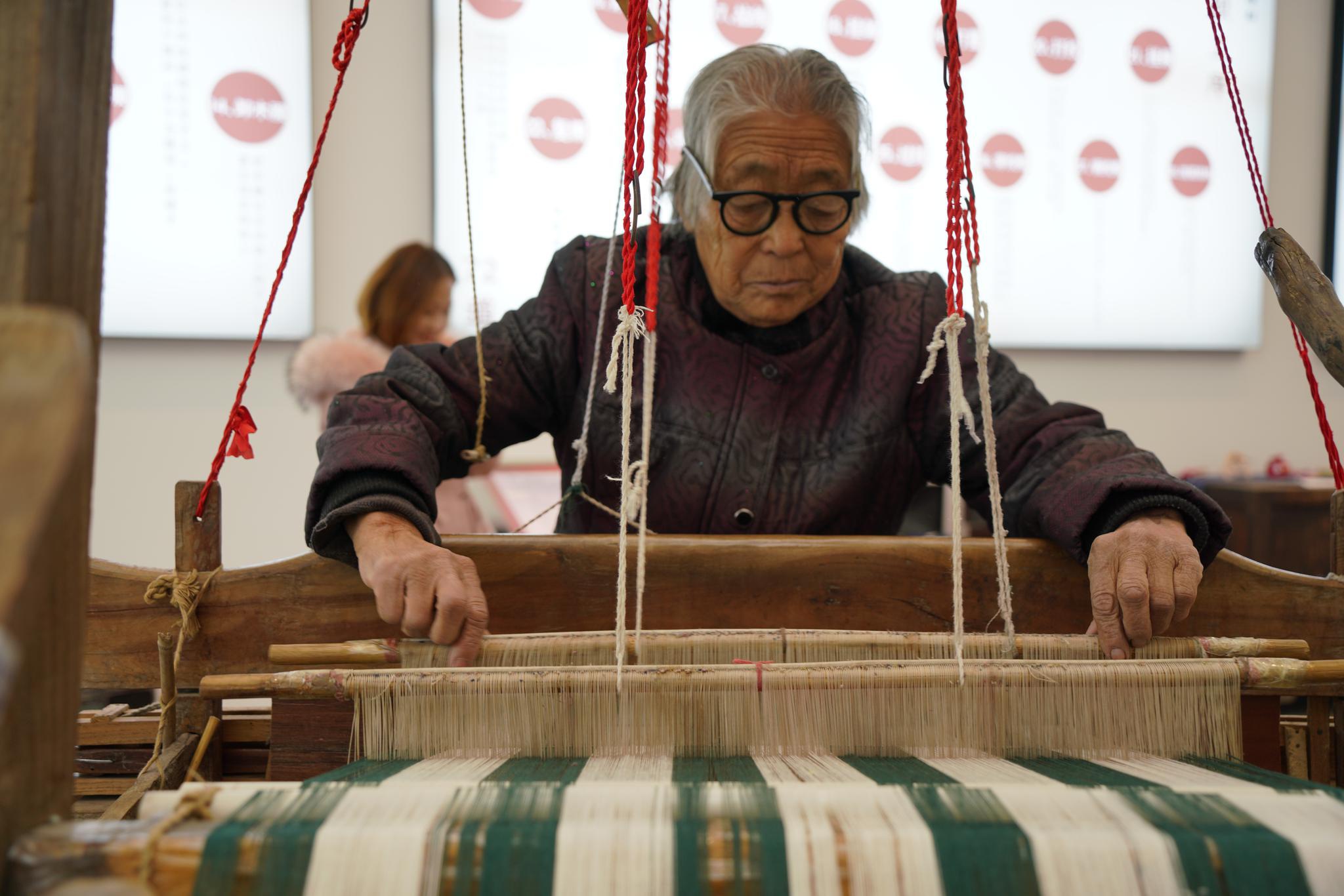 白发苍苍的老人正在熟练的操作织布机.