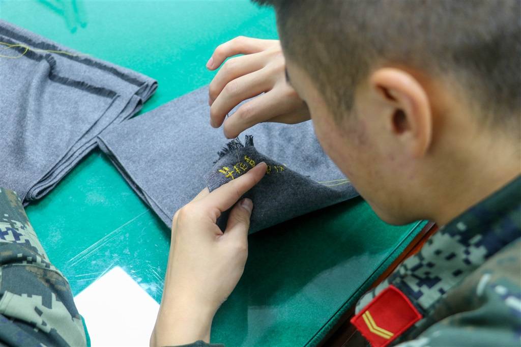 武警战士在赠送阿姨的围巾上缝制结对对象姓名.黄健/摄