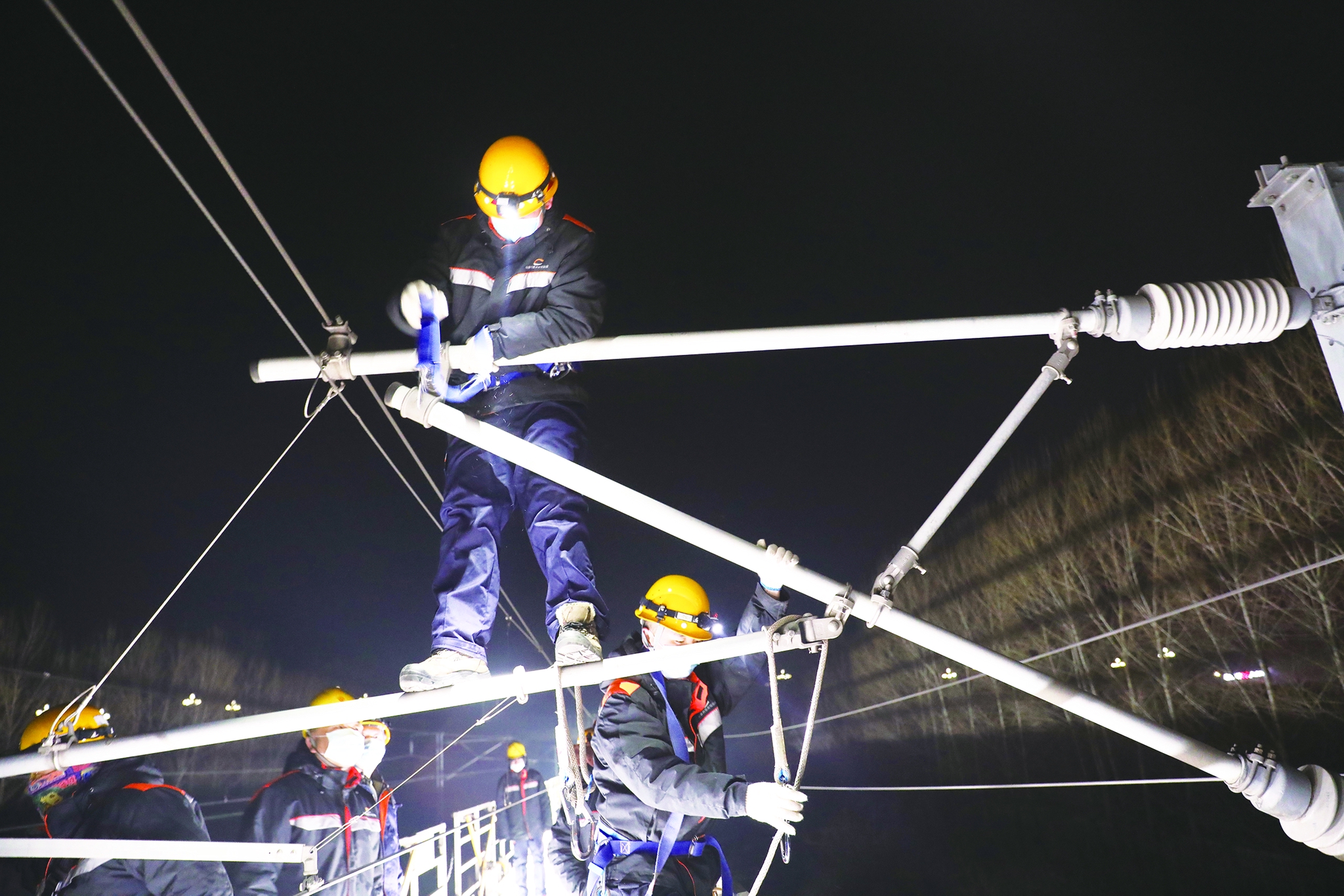 高铁接触网检修工头戴安全帽,身穿反光服,对架在空中的接触网进行检修
