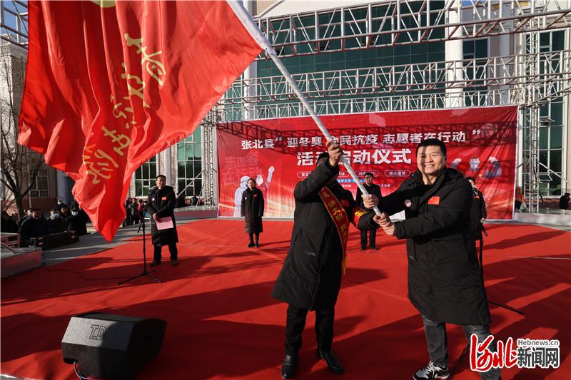 共青团张北县委书记韩世奇(右)向蓝天救援队张北分队长张忠山授旗.