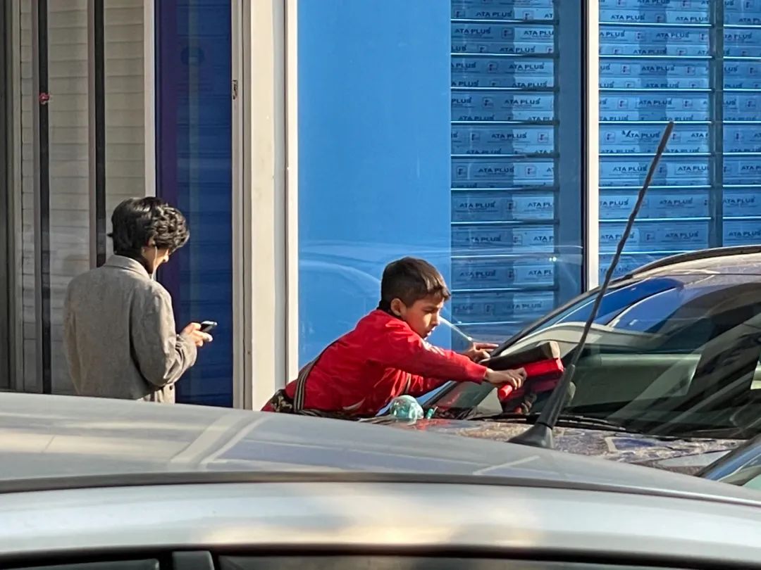 伊朗首都德黑兰街头，一名男孩在擦车。新华社记者高文成摄