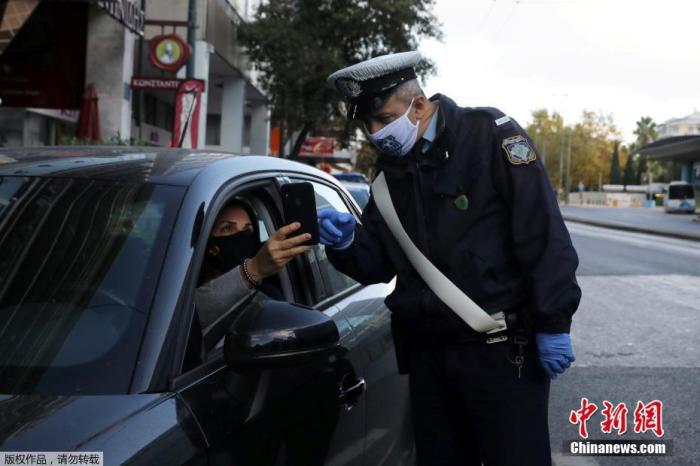 资料图；当地时间2020年11月7日，希腊雅典，一名警察正在检查司机证件，确定其出行目的。