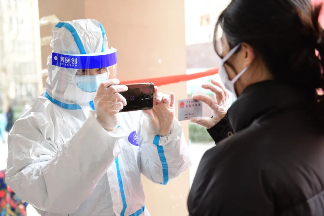 △16日，石家庄新乐市一小区，医护人员正在为居民身份证进行拍照上传核酸检测信息。