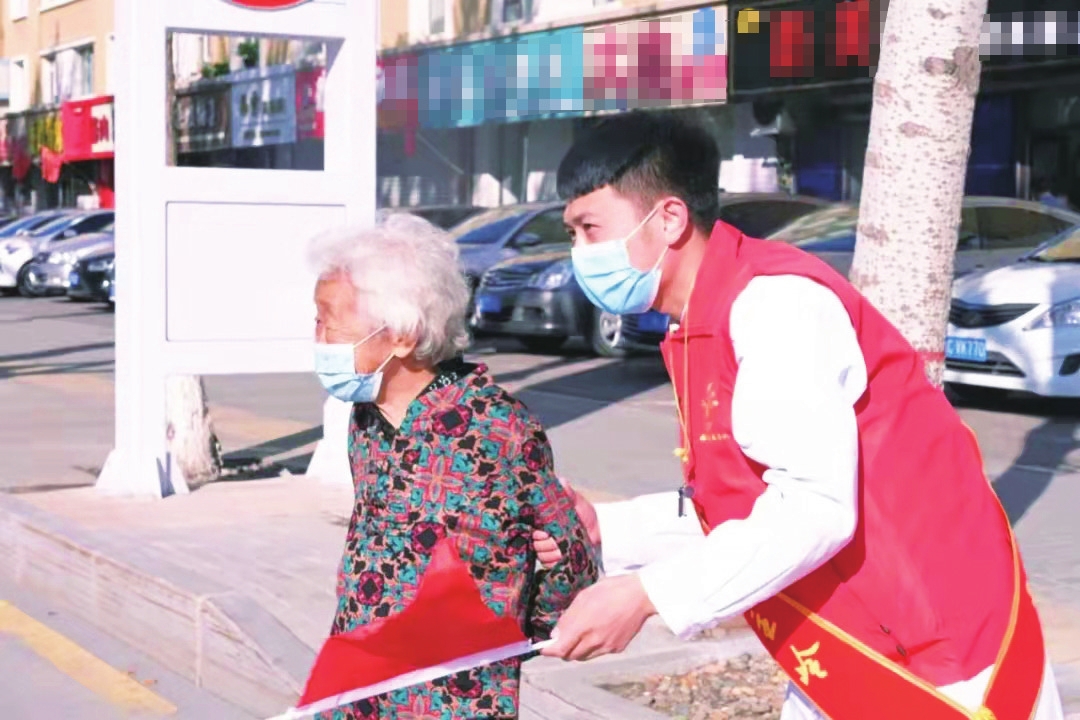 志愿者在文明交通活动中扶老人过马路.(资料图片)