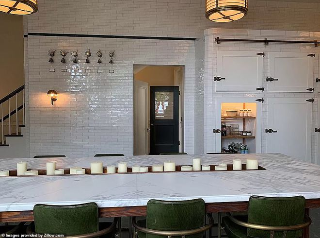 图5：全白色厨房有长长的大理石桌子、木制食品储藏室门以及配套的瓷砖