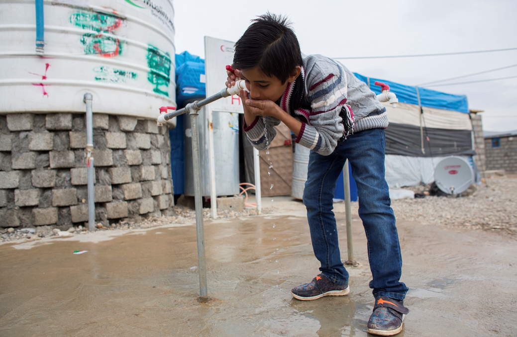 资料图：伊拉克儿童在难民营前喝水