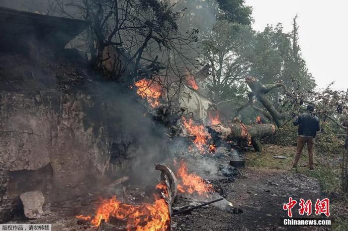 当地时间12月8日，印度南部泰米尔纳德邦，一架印度军用直升机坠毁。事故造成包括印度国防参谋长在内的13人遇难。图为一名男子站在燃烧的飞机残骸旁。