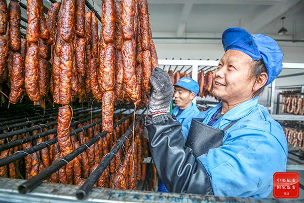贵州省黔西市钟山镇白龙社区腊肉加工车间的工人正在腌制腊肉,香肠等