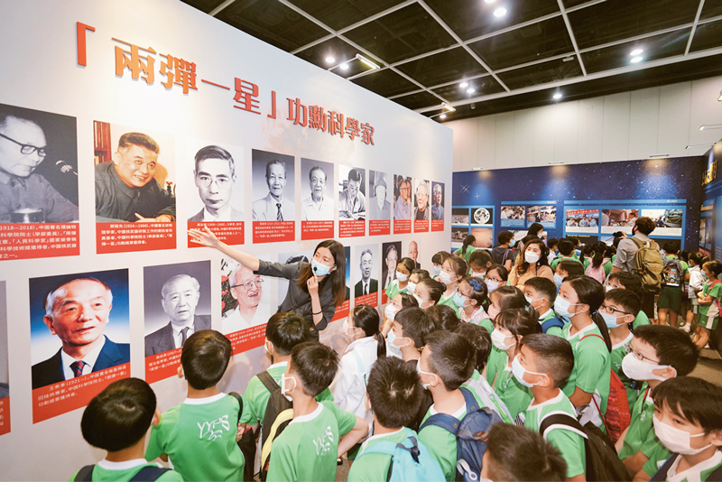 2021年6月27日至7月9日，“时代精神耀香江”之百年中国科学家主题展在香港向公众开放。图为7月7日，众多小学生仔细聆听讲解员的介绍。 中新社记者 张炜/摄