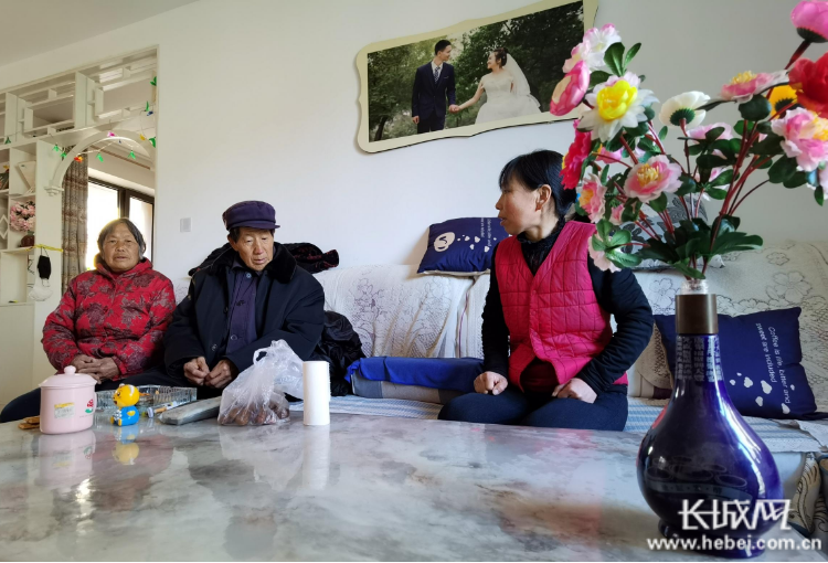 在搬迁后的新房子里，韩彦荣（右一）向父母介绍近期的生活情况。长城网记者 郭庆敏 摄