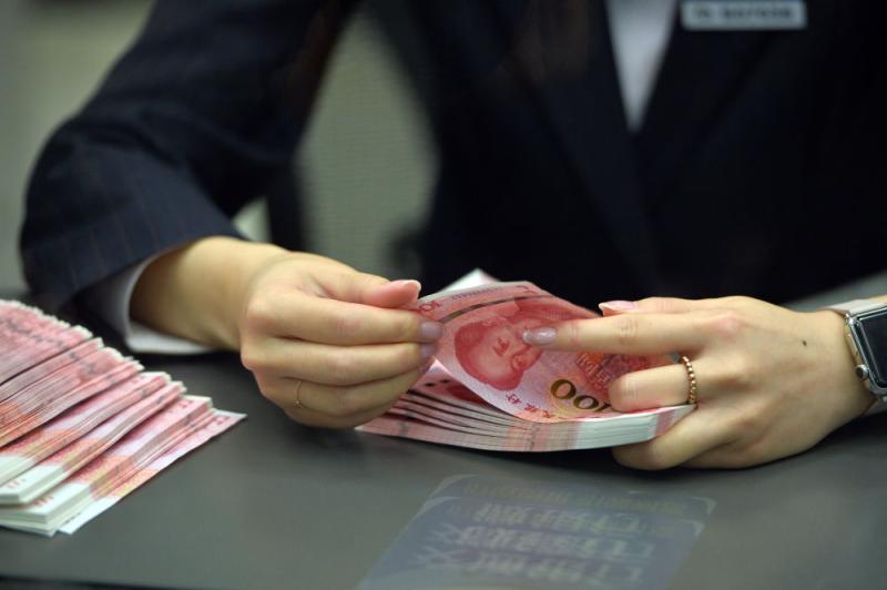 图为一名银行工作人员在清点钞票。 新华社记者 李鑫 摄