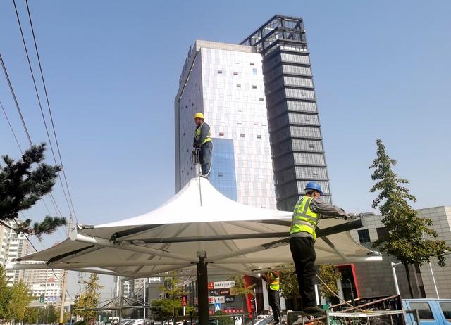 潍坊市文化路民生街路口,工人正在加紧搭建遮阳棚.