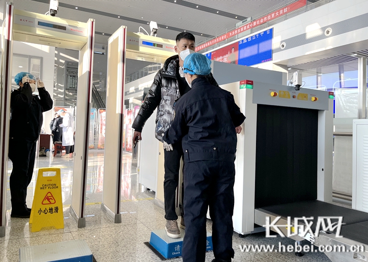 平泉北站工作人员防护在岗,为进站旅客进行安检.