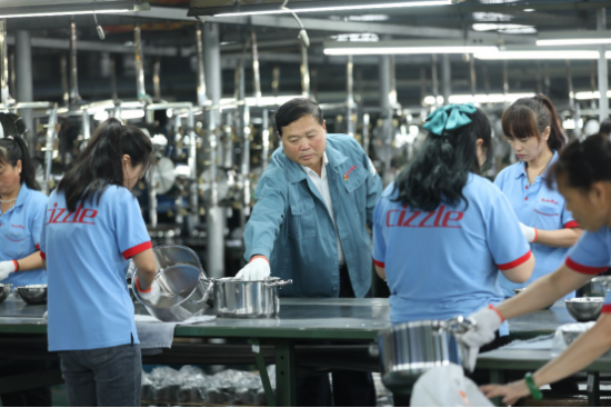▲冠华不锈钢创始人黄勇（喜时董事长黄华峰之父）在生产车间巡查产品的生产情况。