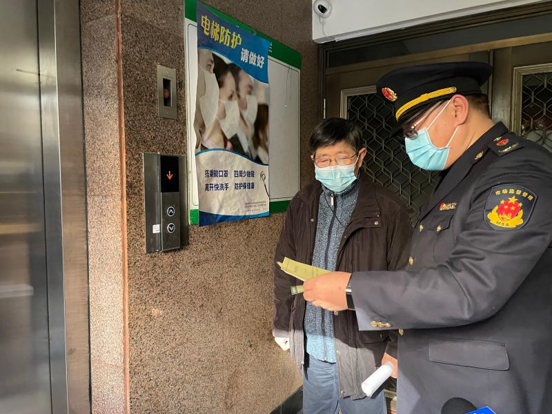 市场监管部门向小区业委会代表出示电梯"上岗证"