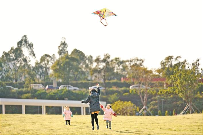 光明区楼村湿地公园内,市民带着孩子在暖阳下欢快放风筝.