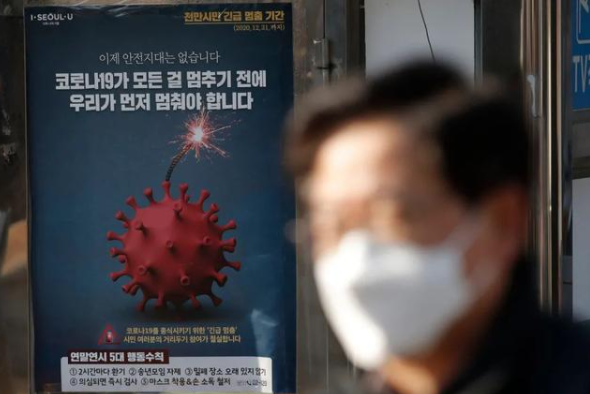 ↑别名戴口罩的外子走过韩国首尔一处宣传抗疫的海报图据韩国日本的一级片