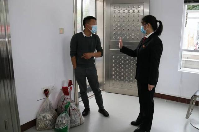 图为法院工作人员正在和叶某望就硬币交款一事沟通。左下角为他带来的4袋硬币。图片来自海城区法院