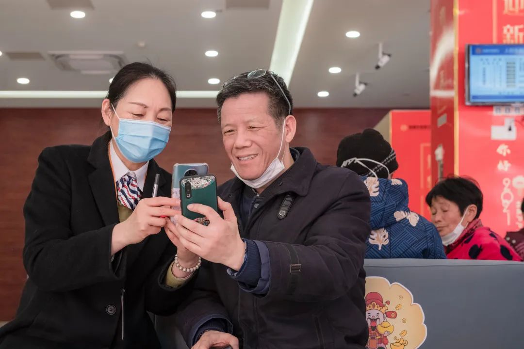 图为蔡吴敏帮助客户使用手机银行app.