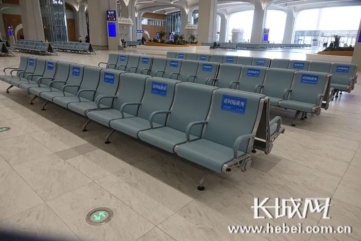 雄安站首层候车大厅内的座椅靠背上均已粘贴"请间隔就座"标识.