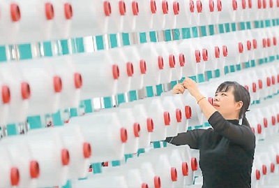 浙江省德清县在用工保障、金融扶持等方面出台惠企政策，推动企业满产达产、扩能提产。图为日前在德清县禹越镇的明品纺织品有限公司车间里，工人在纺纱生产线上操作。谢尚国摄（人民视觉）