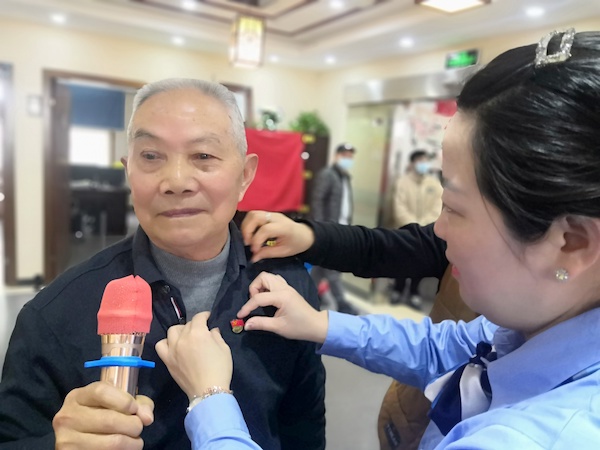 图说:周浦分公司党员志愿者为老人唱红歌,带党徽