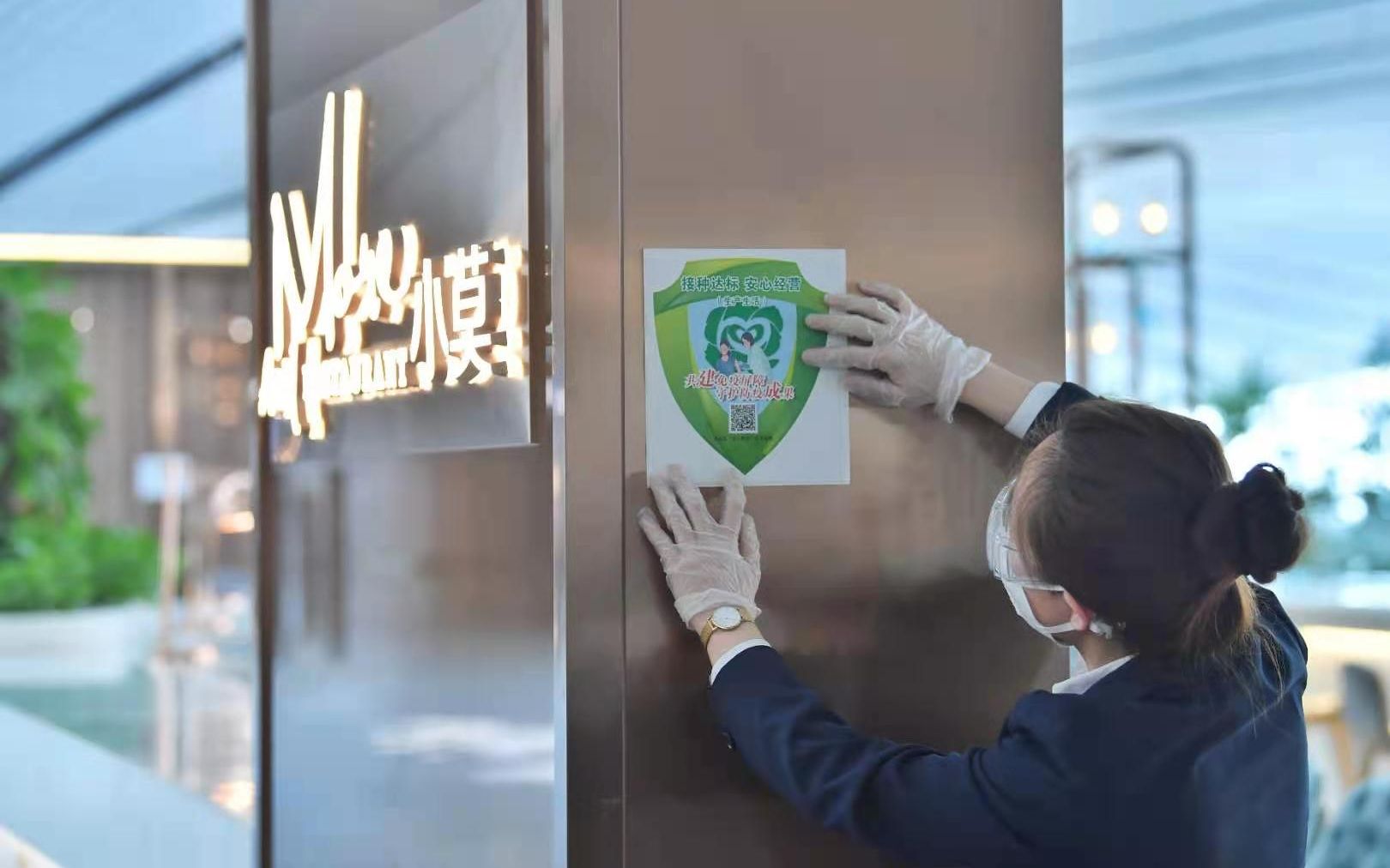 大兴机场航站楼内，工作人员在张贴“安心标”。摄影/新京报记者李木易