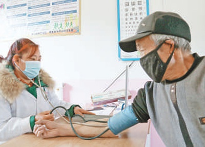 山西宁武县西马坊乡后吴家沟中心村卫生室医生王爱林（左）在为村民看病。本报记者 乔 栋摄