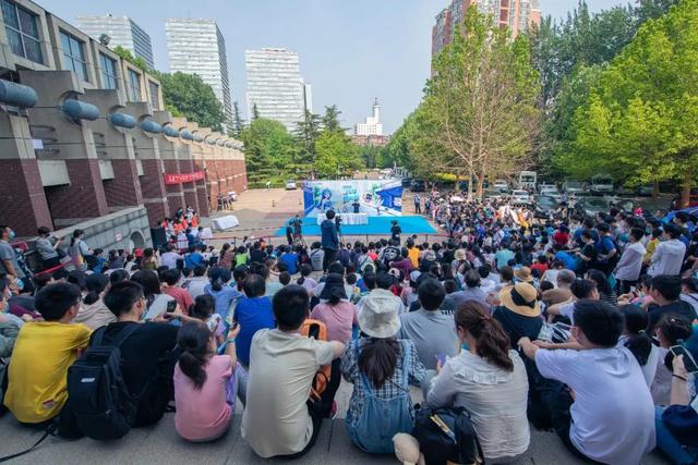 （图说：今年公众科学日，观众席地而坐，围观由B站UP主和大学教授带来的户外大型实验秀）