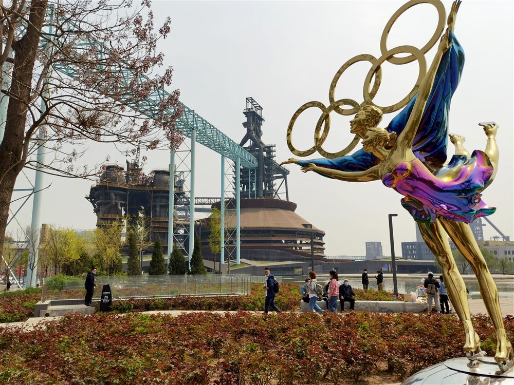 北京首钢园也是冬奥会场馆之一,图中近处为首钢园内的奥运雕塑,越方