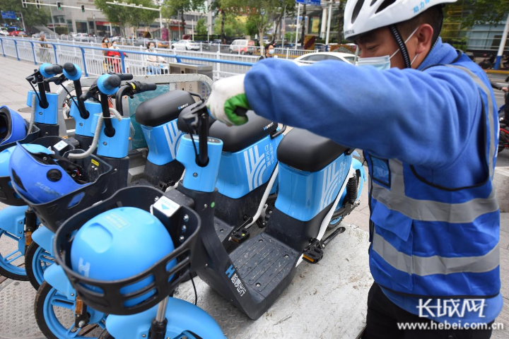 闫奋君正在石家庄中山路与东大街交口整理共享电动车