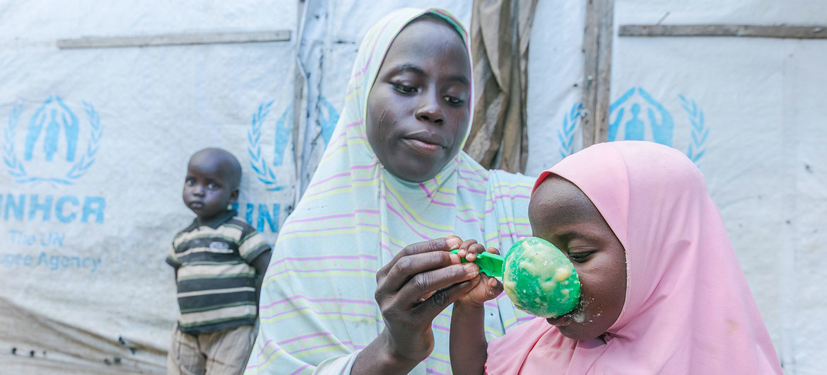 △尼日利亚一位母亲为孩子喂食从世界粮食计划署（WFP）分发站点获得的救助粮食。（图片来源：联合国网站）