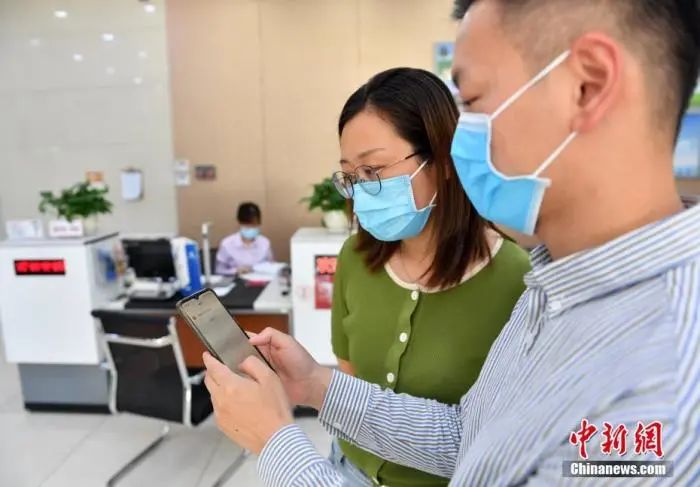 图为6月18日，银行工作人员向市民演示如何查询以“数字人民币”形式领到的工资。中新社记者韩冰摄
