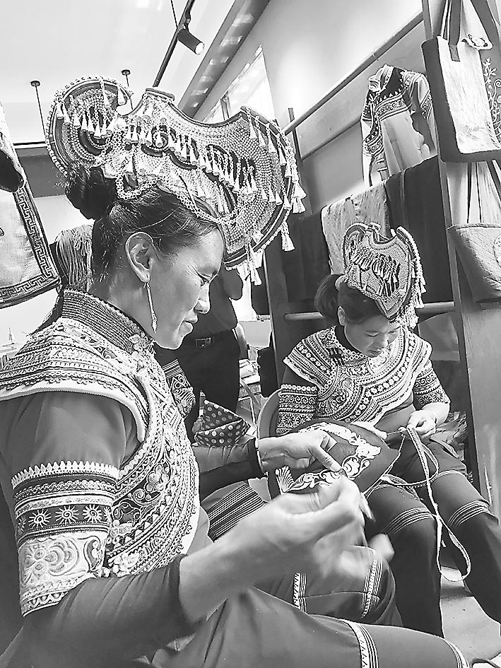 彝族绣娘李世芬（左）在制作传统服饰。毛立军 摄