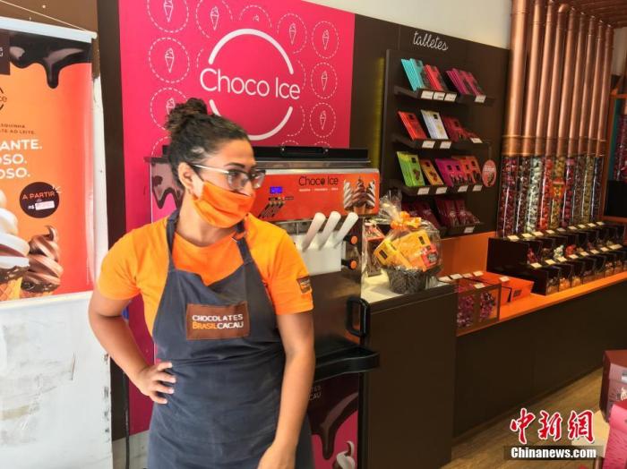 资料图:巴西圣保罗,一名女店员戴着口罩在一家巧克力店推销圣诞礼品。中新社记者 莫成雄 摄