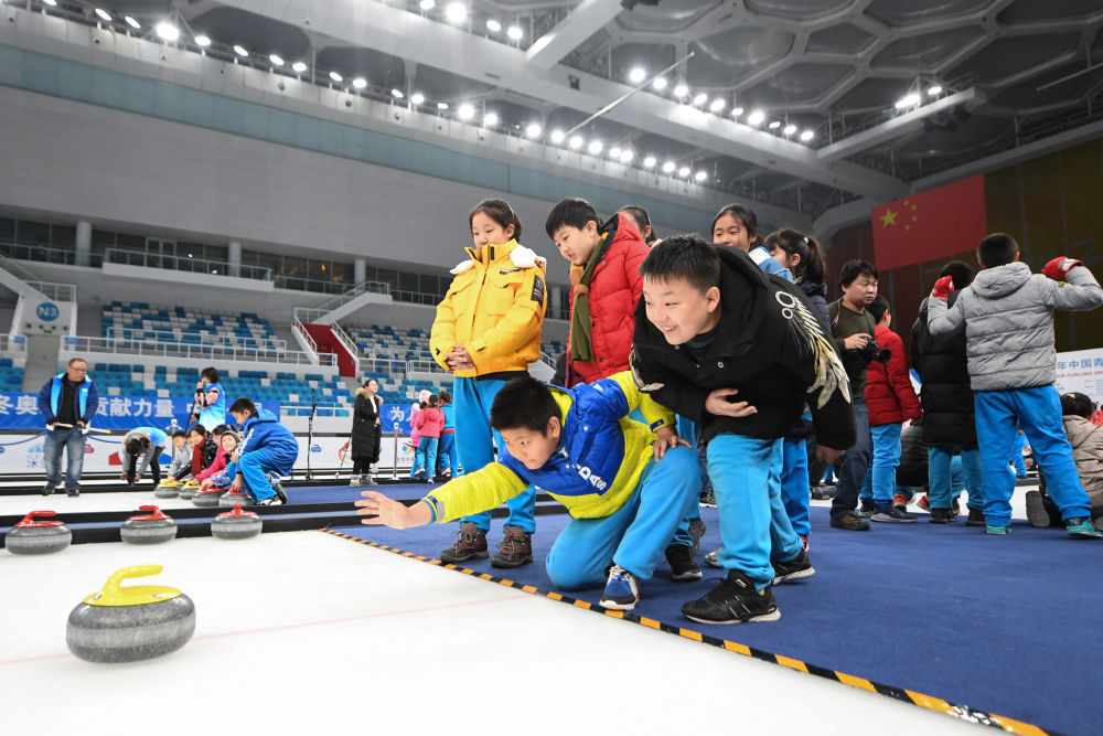 ↑2019年12月10日，北京史家实验学校的学生在“冰立方”体验冰壶。“水立方”国家游泳中心变身“冰立方”，成为世界首个实现“水冰转换”的场馆，未来其南广场地下建设的冰场将全年面向群众开放，为全民冰上运动做好服务。