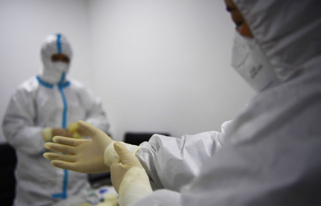 1月8日，郑州市一核酸检测点，医务人员在穿戴防护服。（新华社记者张浩然 摄）